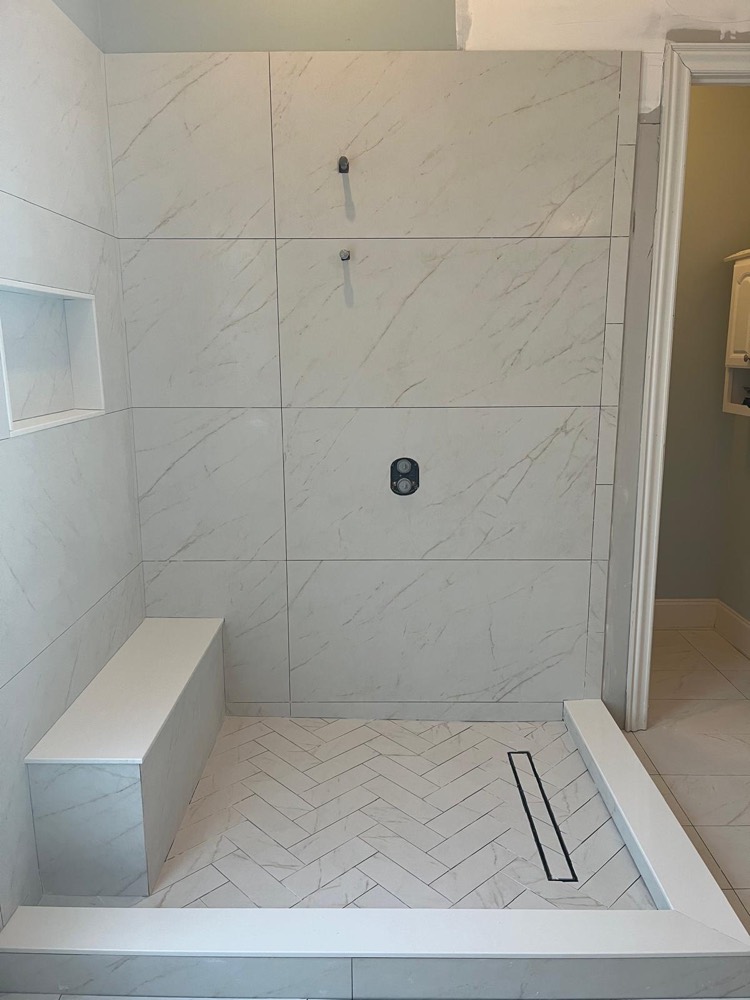 White marble shower with herringbone floor